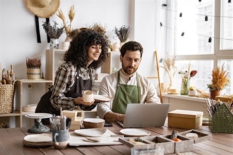 Two people looking at a laptop in a cafe style room