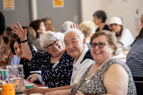 A group of smiling seniors sitting together at Monash Seniors Festival Notting Hill Neighbourhood House community lunch