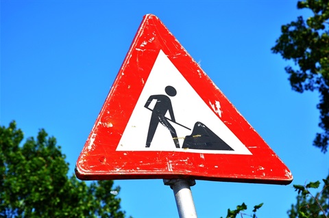 under construction sign shows black image of man digging