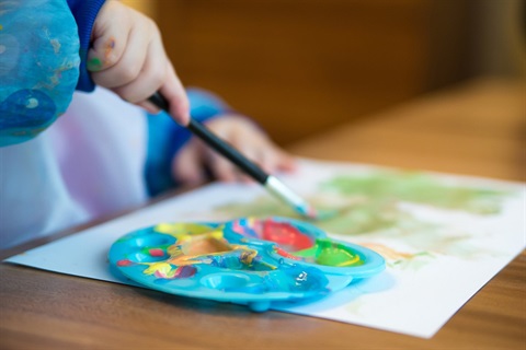 child with an art smock on painting on paper