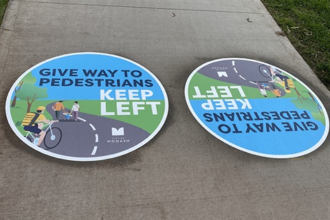 Image of stickers on footpath reminding users to keep left and give way to pedestrians